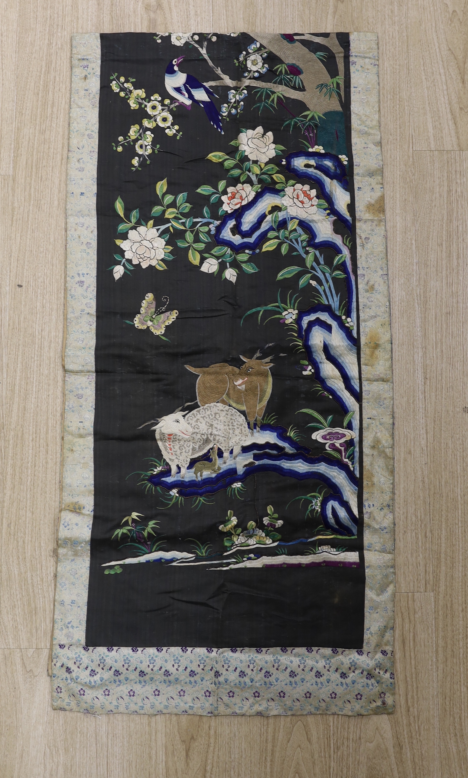 An unusual inscribed 19th century Chinese silk embroidered wall hanging, depicting animals, birds butterflies and flowering trees within a silk brocade border